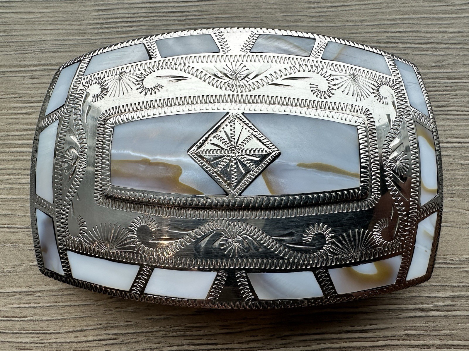 vintage western-style silver belt buckle featuring mother-of-pearl inlay. vintage western-style silver belt buckle featuring mother-of-pearl inlay.