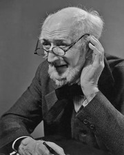An old man wearing glasses cups his ear in his hand circa 1940's Old Photo picture